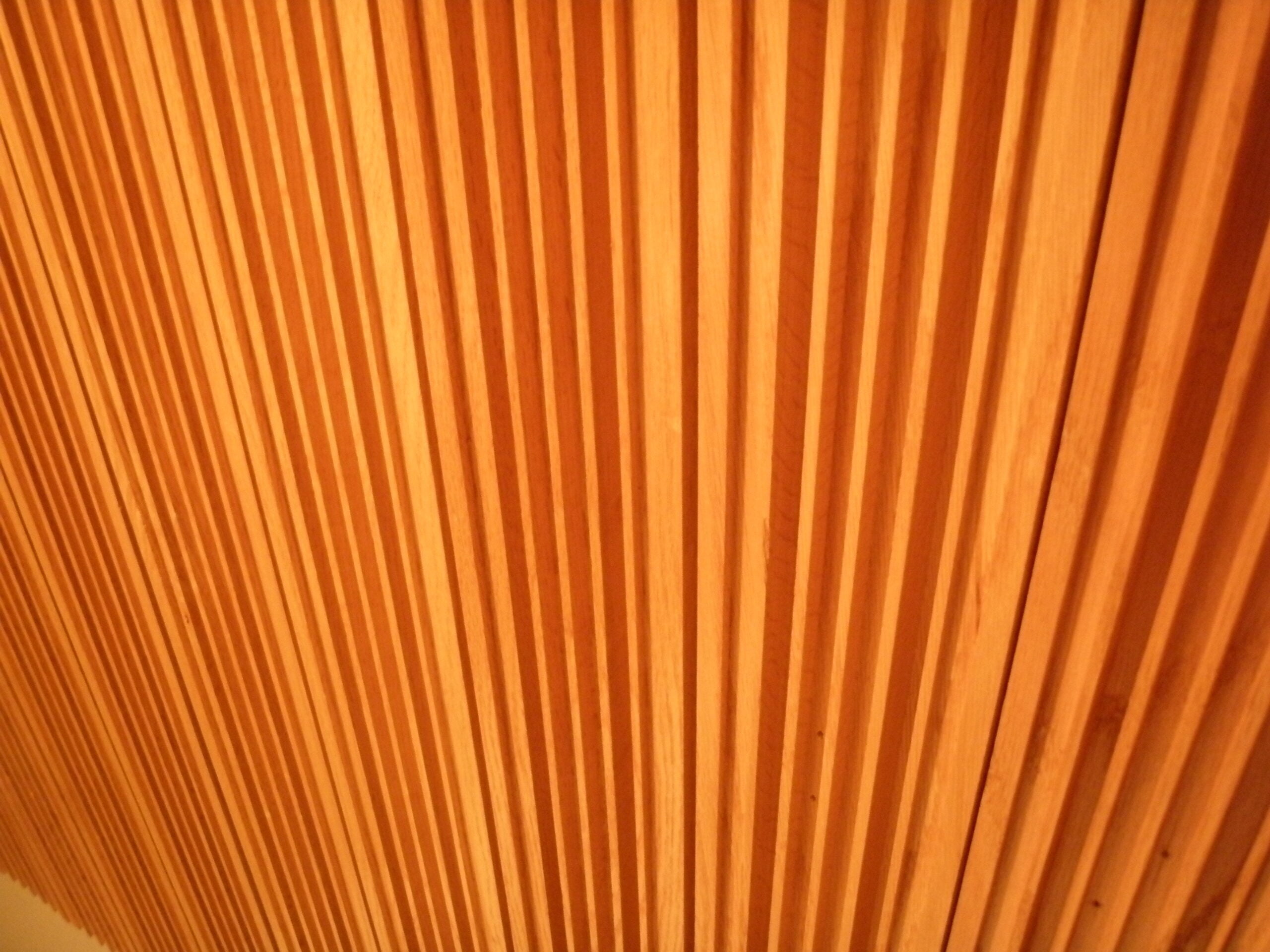 A close-up of a wooden slatted ceiling with warm lighting.