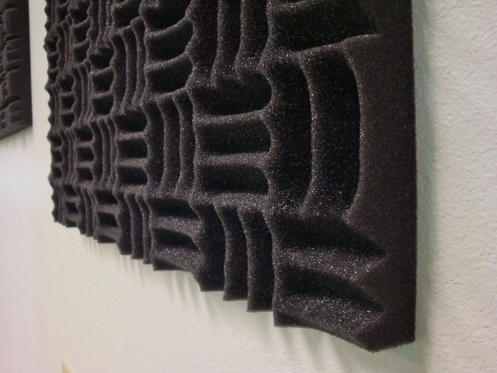 Black acoustic foam panels with a geometric pattern mounted on a white wall.