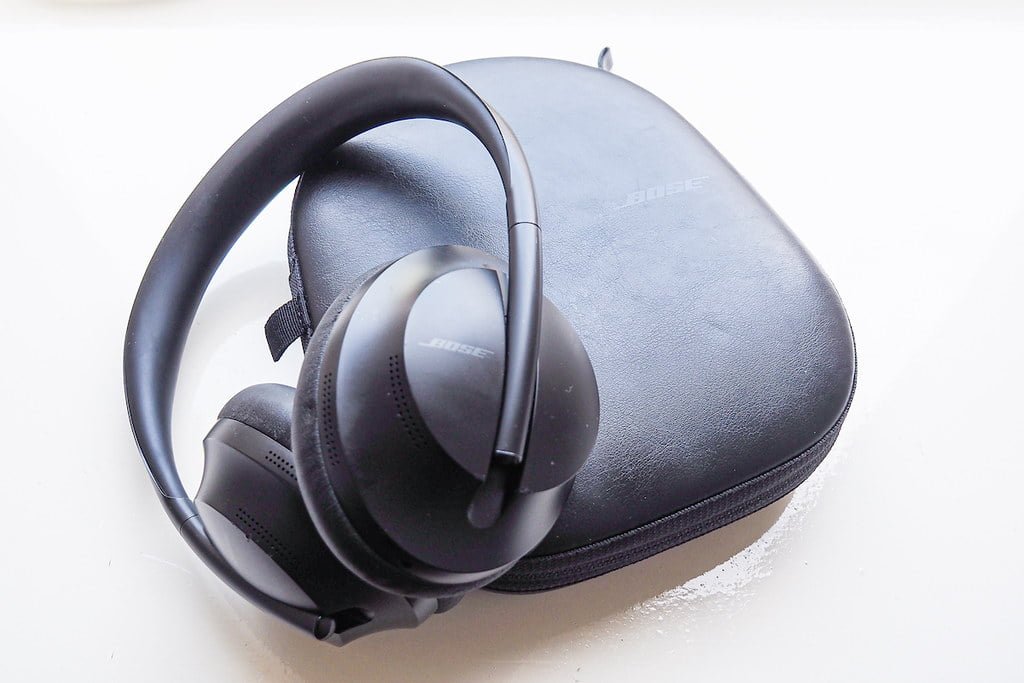 Bose headphones placed next to their carrying case on a white surface.