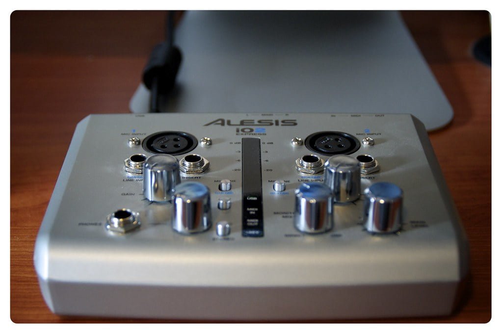 A close-up view of an Alesis IO audio interface with focus on its control knobs and input ports on a wooden surface.