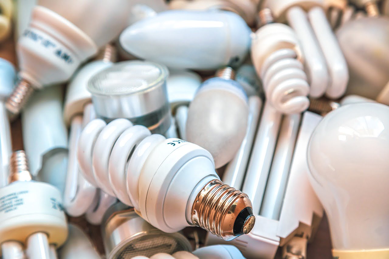 A variety of light bulbs, including CFL, LED, and incandescent types, are closely packed together.