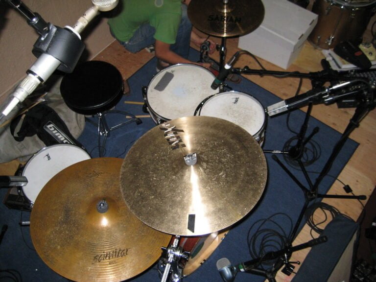 A drum set with various microphones positioned around it for recording, including brands like Sabian visible on the cymbals.