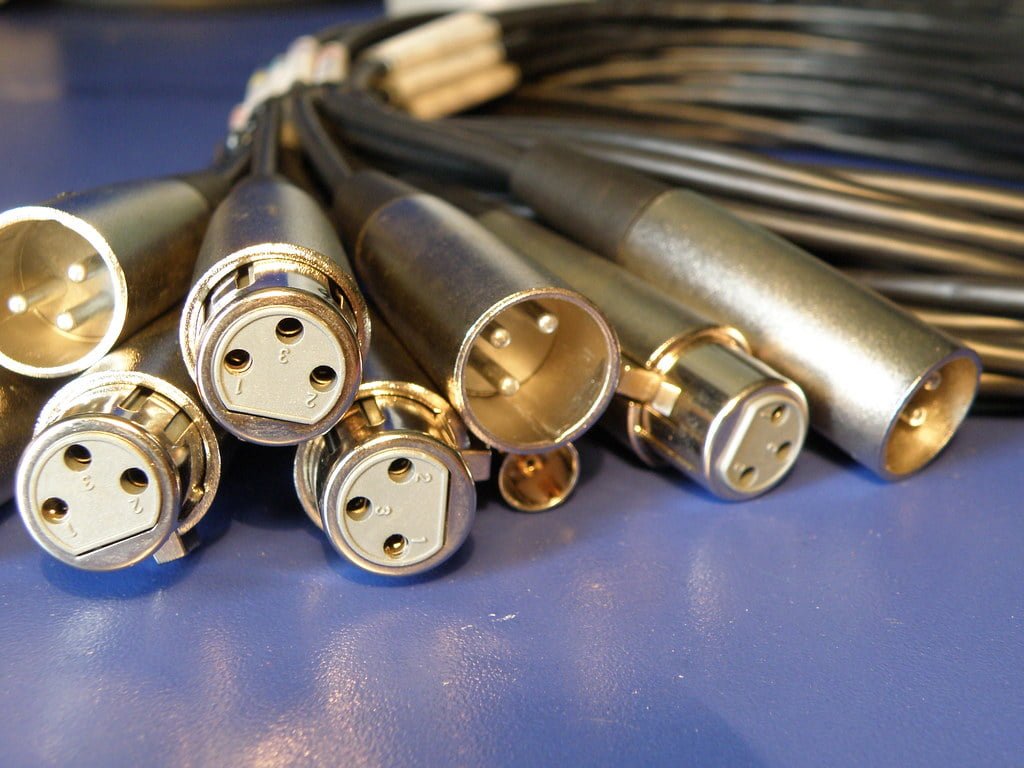 A collection of XLR connectors on cables against a blue surface.