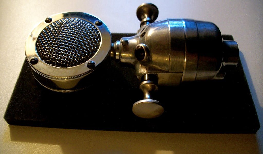 Vintage silver microphone with a circular grille on a black base.