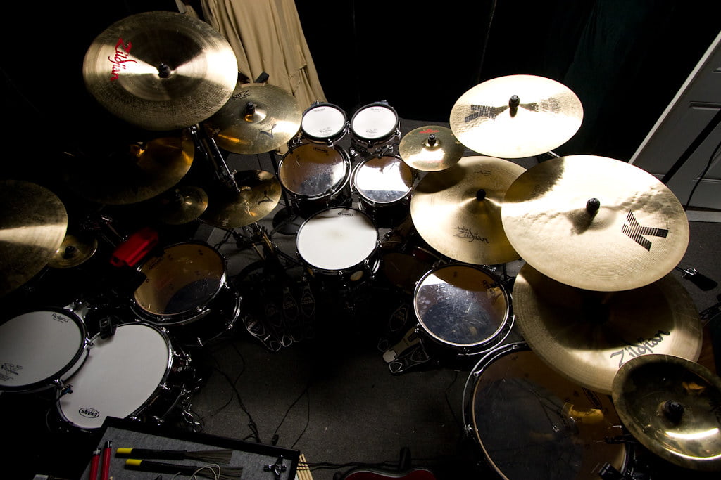 A top-down view of a drum set with various cymbals illuminated by a spotlight.