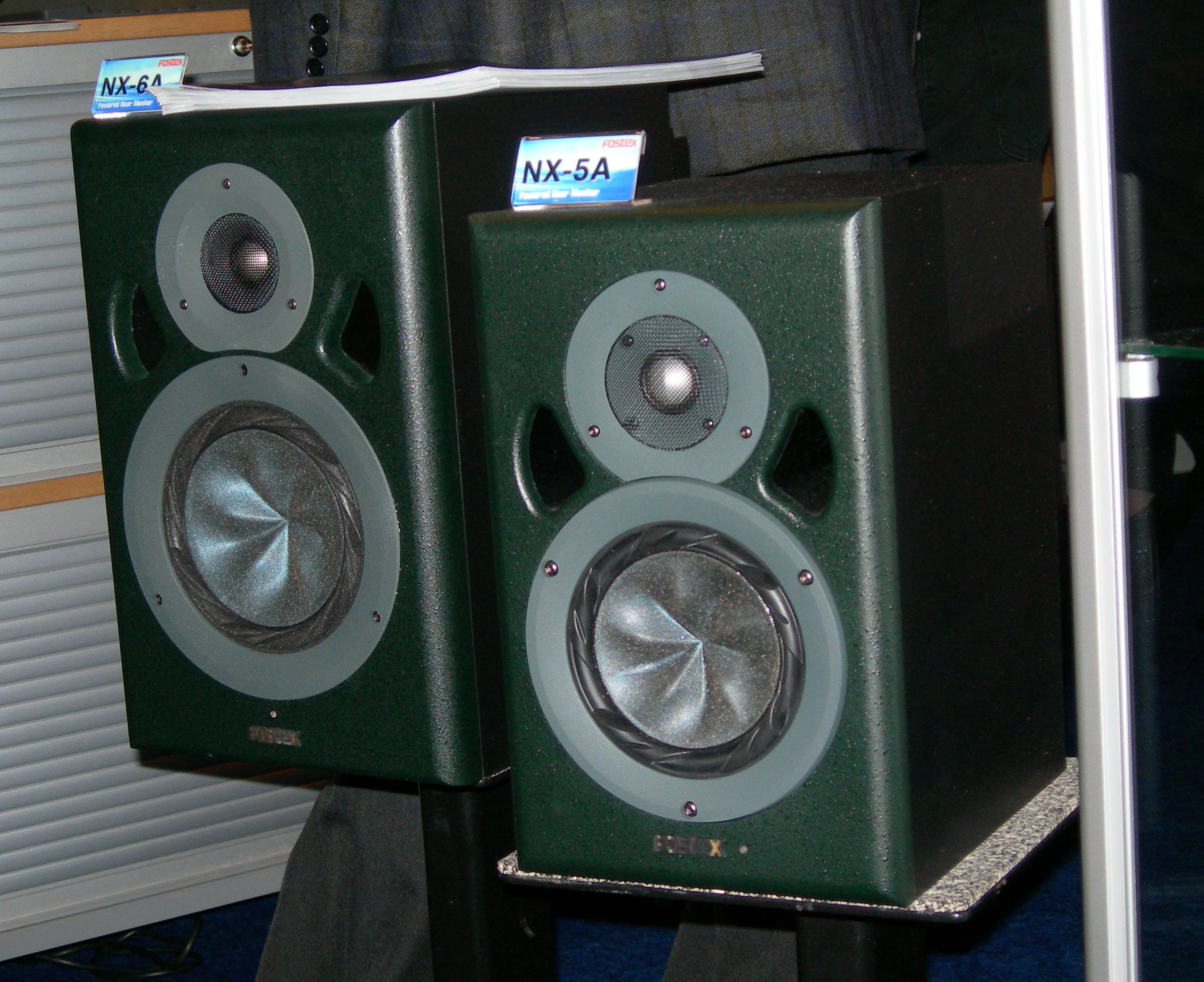 A pair of green NX-5A professional studio monitor speakers on a floor with small placards displaying the model number.